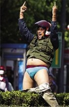 A Thai red shirt protester flips the double bird, while straddling a bush with his pants down and wearing a motorcycle helmet